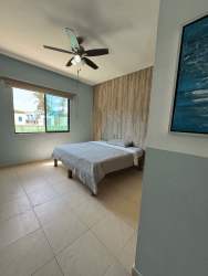 Bedroom with light blue wall accent ceiling fan large window Playa Blanca Resort condo Panama beach area