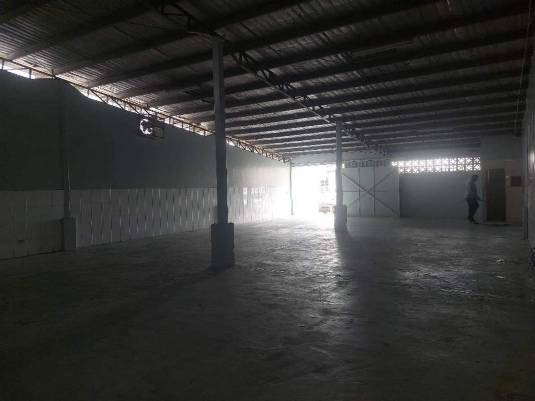 Spacious warehouse with metal roof, concrete floor, ventilation fan and large sliding metal gate in Panama