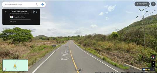 Main asphalt road lined with trees adjacent to open land Sardinas Penonomé Coclé Panama