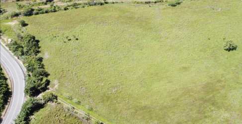 Open grassy vacant plot with mountain background adjacent to paved road Penonomé Coclé Panama