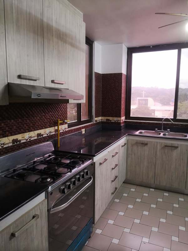 Kitchen with light wood cabinets, large windows, black countertops in PH El Dorado Panama