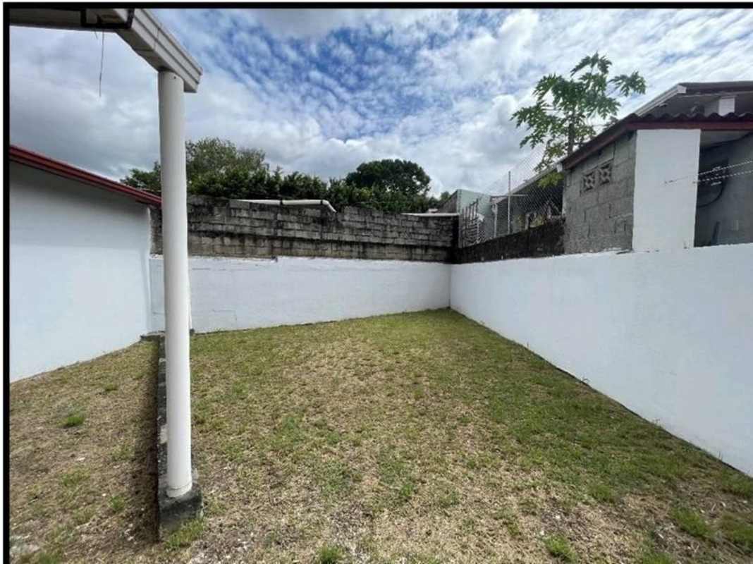Enclosed backyard with white walls and patchy lawn at Cerro Viento Panama home for sale