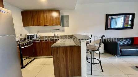 Furnished living room with sofa, TV, open plan kitchen PH Midrise Panama Pacifico