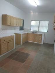 Wood cabinetry, corner counter, windows with bars in Panama beach house kitchen