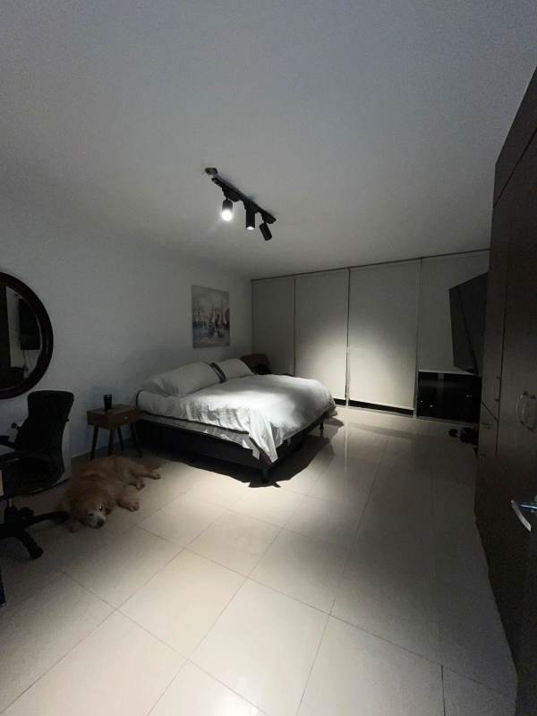 Minimalist home office with computer desk, black sofa, white walls and tile floors at PH Serenity Panama