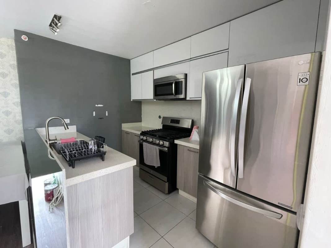 Kitchen with double door fridge, gas stove, microwave, and modern cabinetry in PH Metropolitan Park Panama