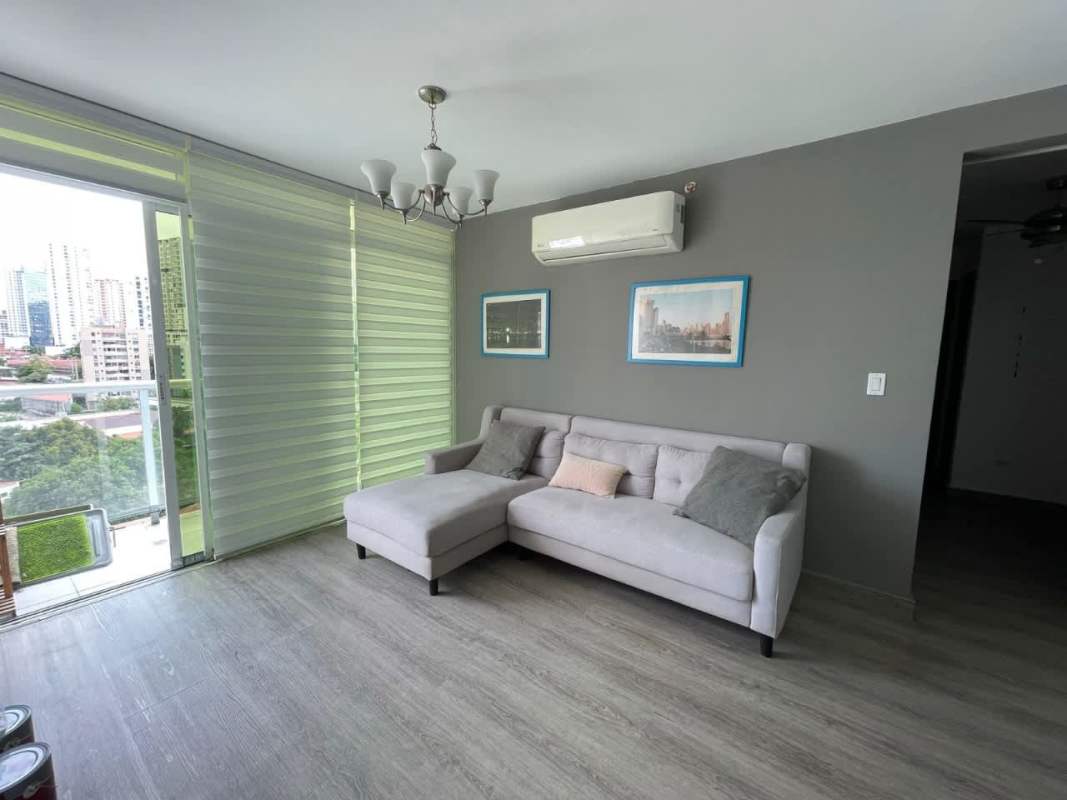 Modern living room with large windows, gray sofa, and city view in PH Metropolitan Park Panama