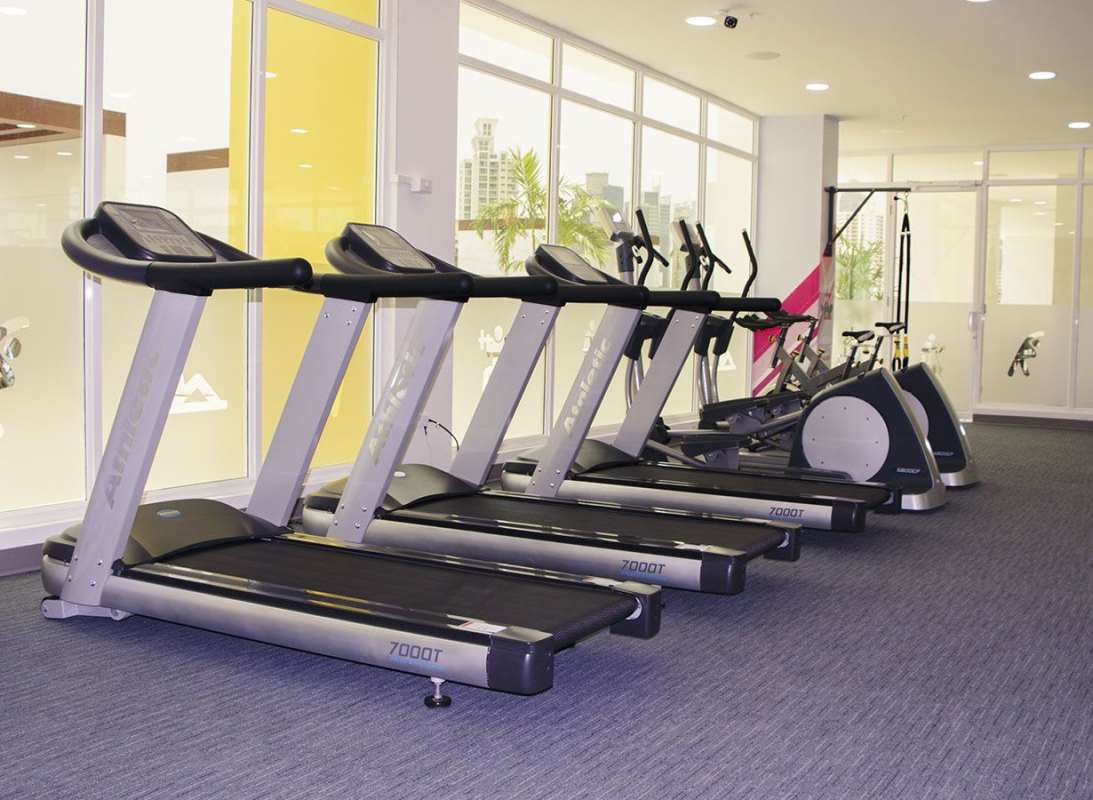 Main bedroom with AC, floral bedspread, ceiling fan, floor-length curtains PH Metropolitan Park Panama