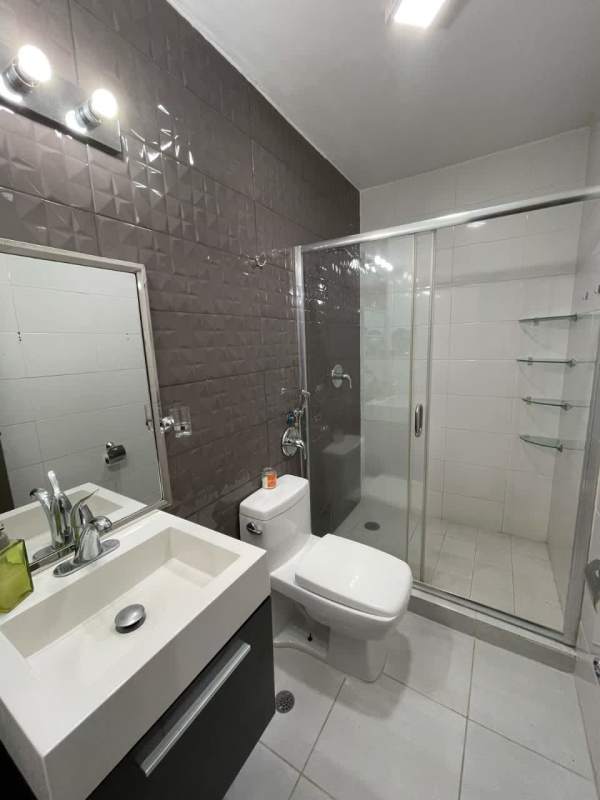 Contemporary bathroom with glass shower, dark accent wall, and modern sink in PH Metropolitan Park Panama