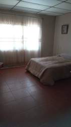 Simple bedroom with large window, tiled floors and neutral decor in Los Algarrobos house for sale