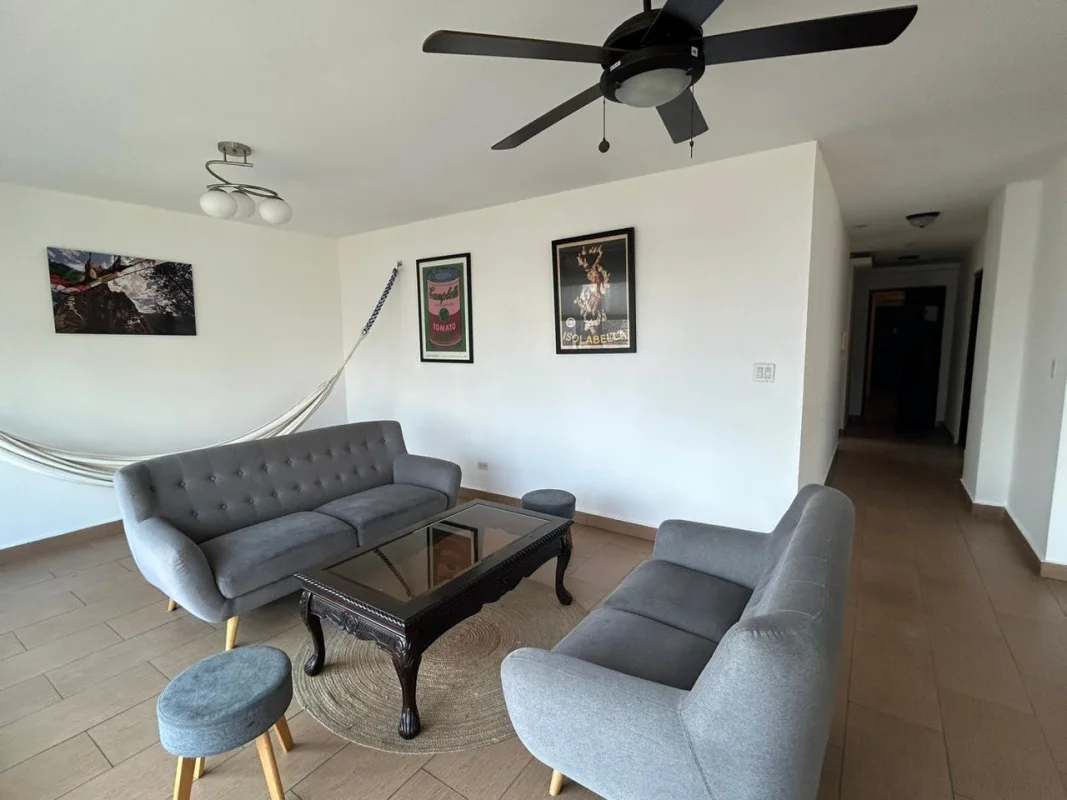 Furnished modern living room with gray sofas, glass table, hammock, balcony access at PH Mediterráneo El Cangrejo Panama