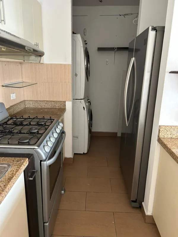 Kitchen with granite counters, refrigerator, gas stove, washer dryer area at PH Mediterráneo Panama City