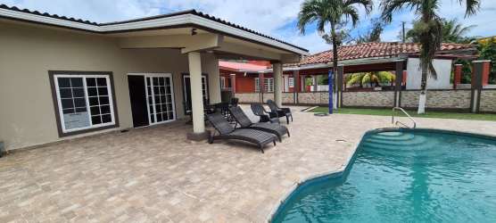 Outdoor terrace with lounge chairs, tiled floor near pool, palm trees at San Marino Ocean Front villa Colón Panama