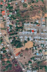 Open green vacant lot area with vegetation behind house in Las Lomas David