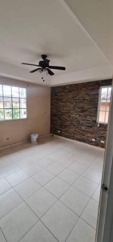 Unfurnished living room with brick accent wall, large windows in Dorado Lake Panama City