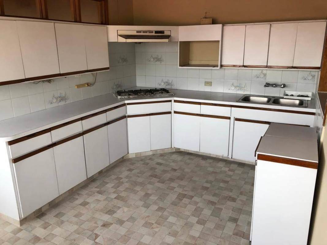 Mid-century kitchen with gas stove, white cabinets, range hood in Betania Panama house
