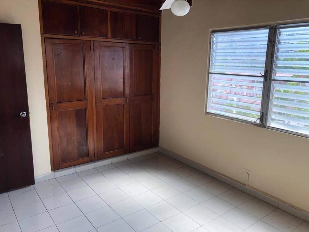 Bedroom space with wood wardrobes, louvered windows, tiled floors in Betania house Panama City