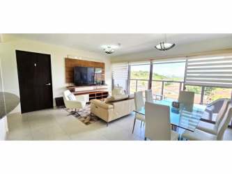 Living dining with balcony overlooking mountains and canal in PH Midrise Panama Pacifico