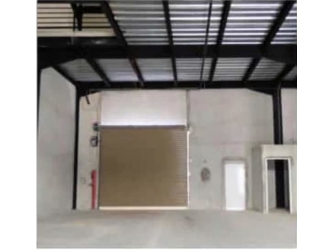 Empty interior of warehouse with high ceiling and metal rolling door in Ancón Panama