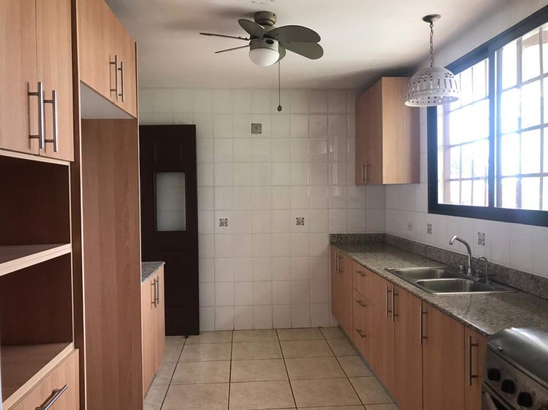 Modern kitchen with granite countertops, wood cabinets, tiled walls and large window in Brisas del Golf San Miguelito Panama