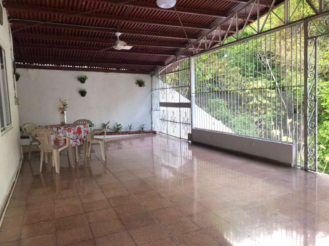 Outdoor covered terrace with tiled floor and greenery in Villa de las Fuentes Panama City