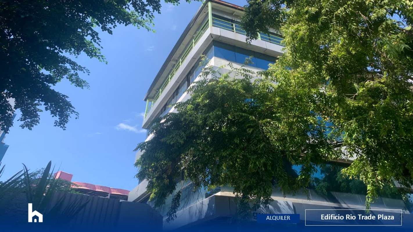 Modern glass facade of Edificio Rio Trade Plaza in Panama City green trees in foreground