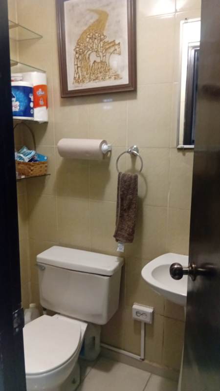 Small tiled bathroom with sink toilet and window inside medical office at Policlinica San Fernando Panama