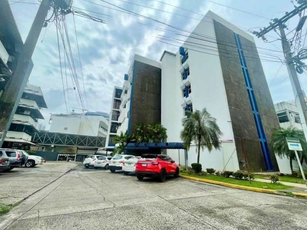 Multi-story building with parking lot palm trees and large windows near 12 de Octubre Panama City