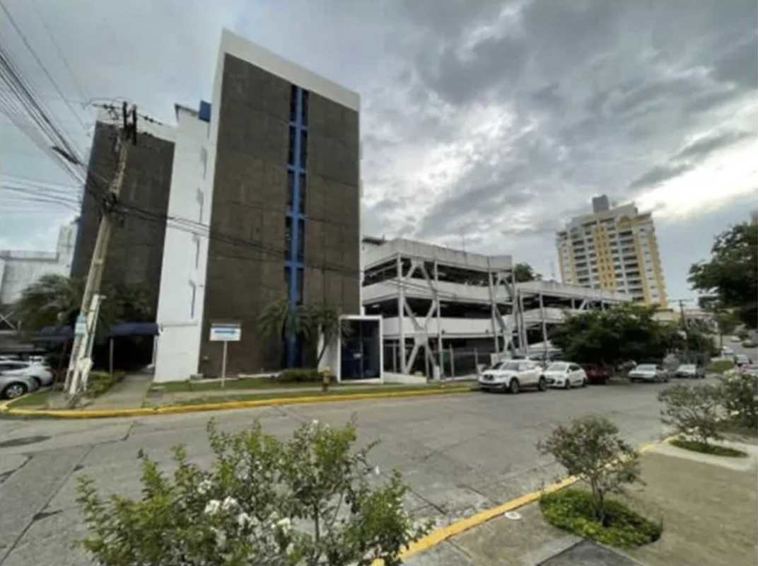 Commercial multi-story building and adjacent parking structure with palm trees in Panama City 12 de Octubre area