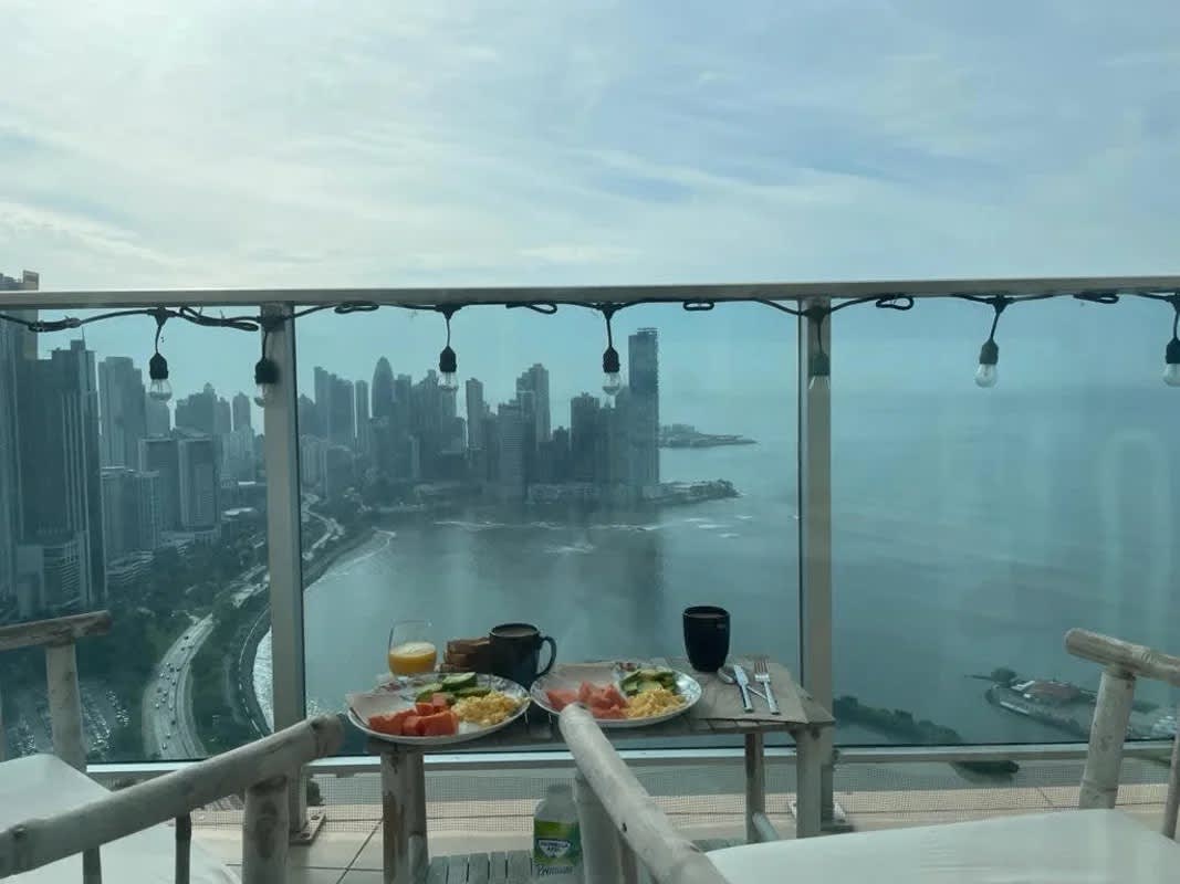 Balcony with breakfast table overlooking ocean and city skyline at PH White Tower Avenida Balboa Panama