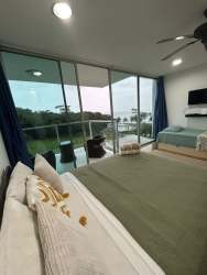 Furnished studio interior with queen bed and sofa bed facing ocean balcony at PH Bala Beach Panamá