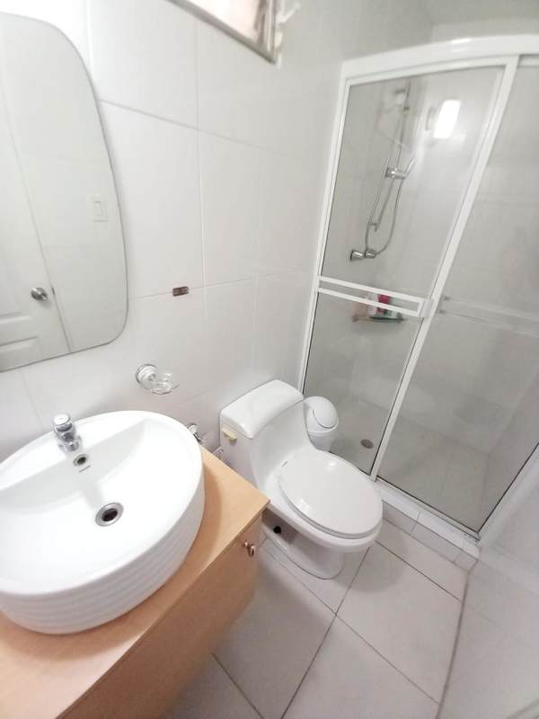 Minimalist modern bathroom with glass shower, white sink, and tile walls in Condado del Rey house for sale
