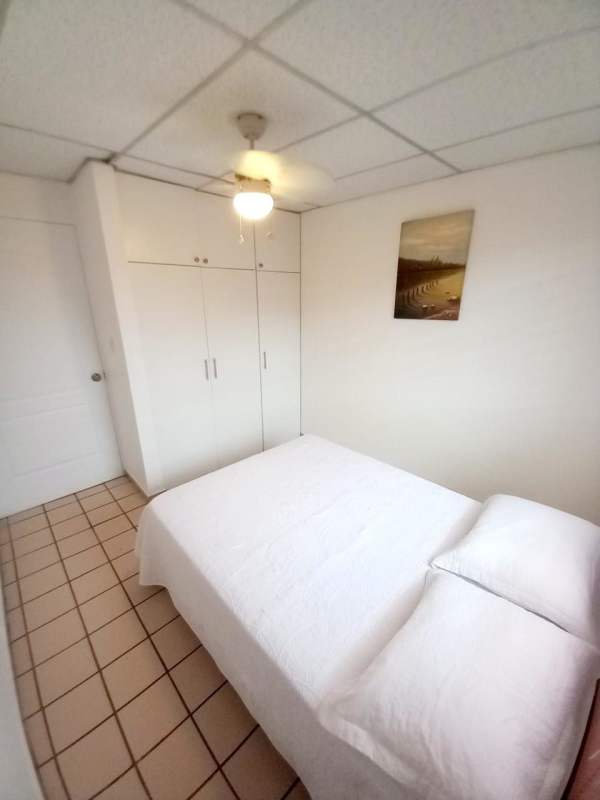 Minimalist bedroom with white bed, wardrobe, ceiling fan, and tiled floor in Condado del Rey house for sale Panama