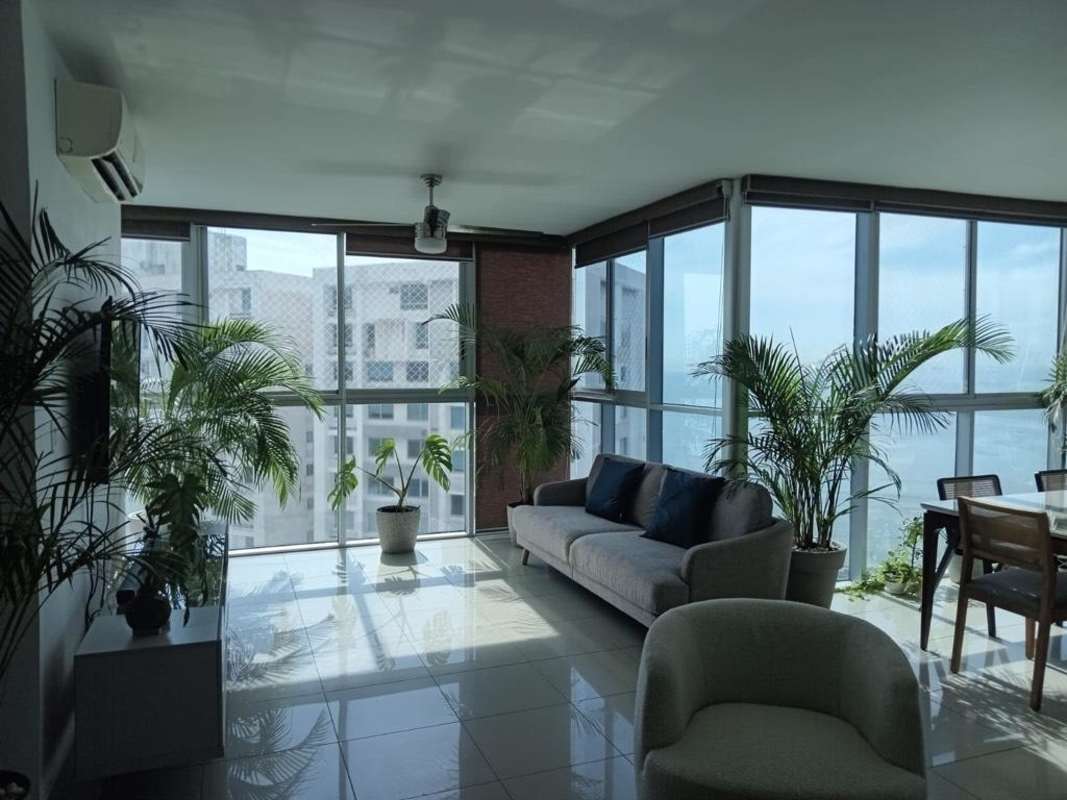 Open-plan dining and living area with panoramic ocean front windows at PH Waterfalls Coco del Mar Panama City