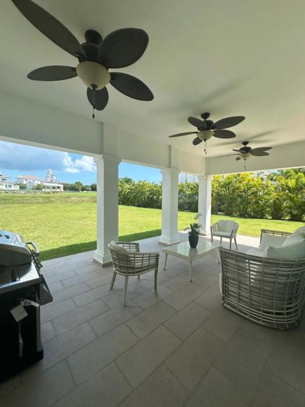 Furnished covered patio with ceiling fans overlooking green lawn in Bijao Beach House for rent