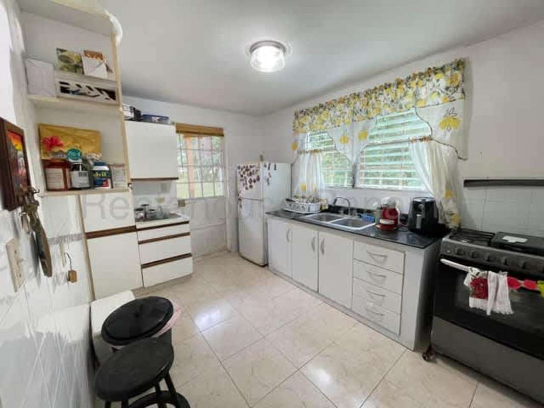Kitchen with white cabinets, gas stove, double sink at Brisas del Golf II Panama house for sale