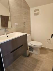 Beige tiled bathroom with modern vanity and mirror in Nativa community house Panama