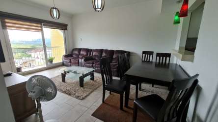 Living room and dining area with balcony access in furnished apartment at Tucán Country Club Panama Pacifico