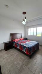 Modern bedroom with large window natural light tile flooring in furnished apartment at Tucán Country Club Panama