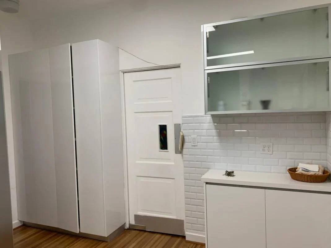 Minimalist modern kitchen with white cabinets and wood floors in house for sale Los Rios Panama