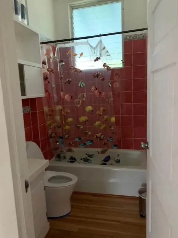 Pink tiled bathroom with bathtub and shower curtain in Los Rios house for sale