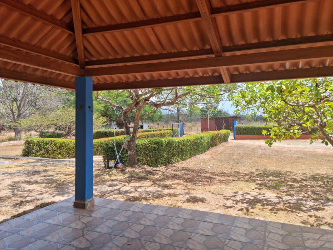 Covered terrace with blue columns overlooking fenced yard and countryside in Chilibre Panama