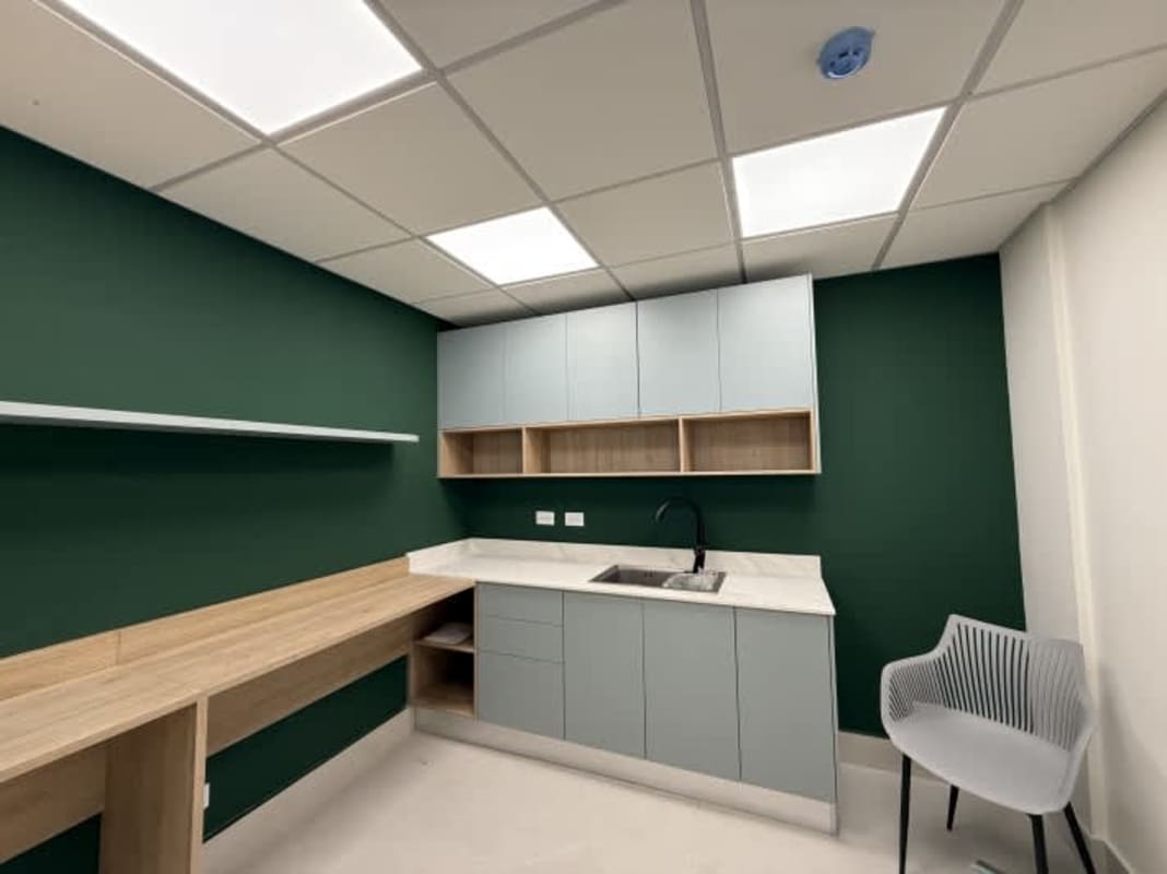 Minimalist kitchenette with marble countertop, mint wall and blue cabinetry in PH Prisma Business Tower Costa del Este Panama