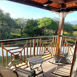 Covered private balcony with patio chairs overlooking lush scenery from beach apartment at PH Coronado Golf Panama