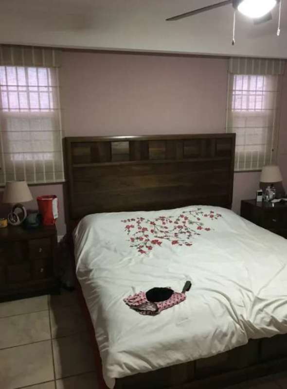 Bedroom with wooden headboard, ceiling fan, large window and tiled flooring in house Brisas del Golf Panama