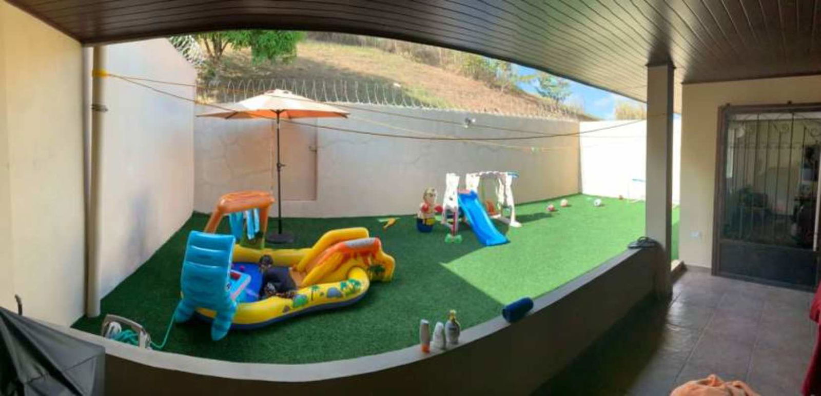 Living room with textured wall, mounted TV, ceiling fan, chandelier and comfy seating in Brisas del Golf Panama