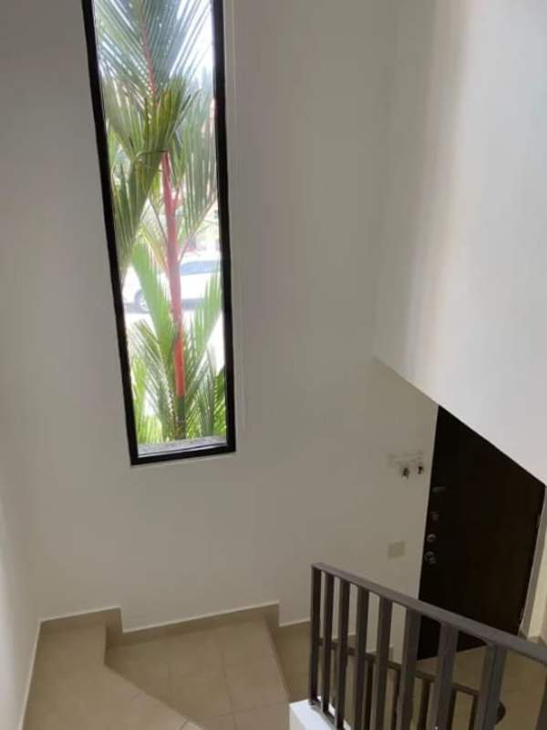 Bright staircase featuring tall window with garden view inside PH Versalles Panama City