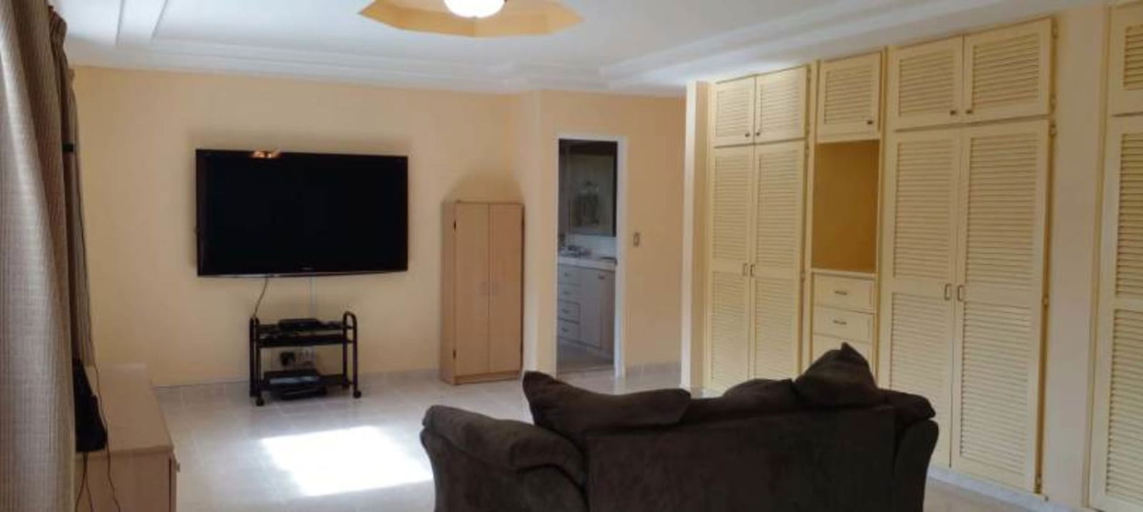 Large living room with built-in closets, TV, ceiling fan in Miraflores Panama house