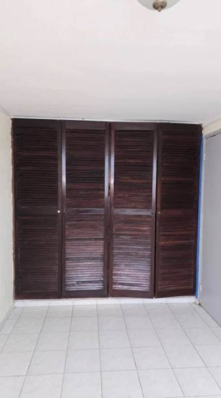 Small bedroom with barred window, single bed and wooden desk PH Parque Lefevre Panama City