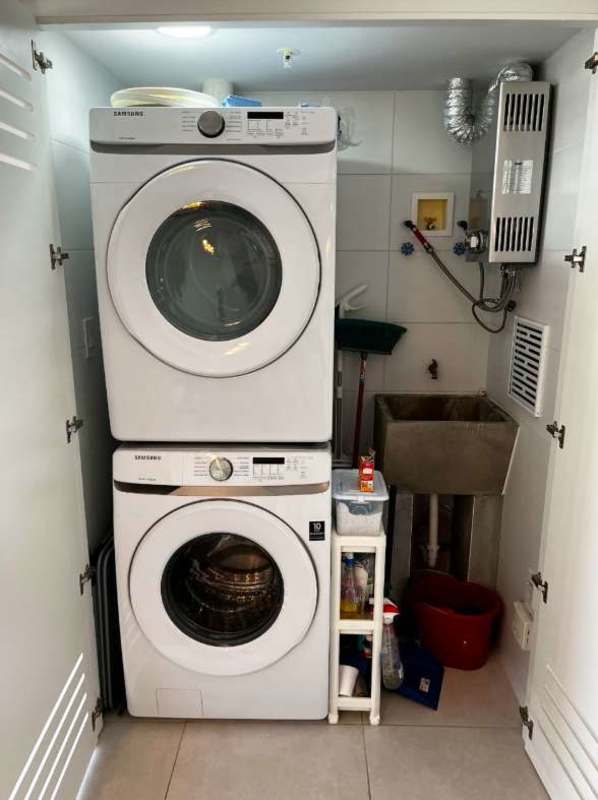 Laundry room in Panama condo with stacked washer dryer, water heater, and utility sink